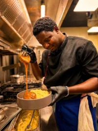 Chef pouring gravy over mashed potatoes and meat
