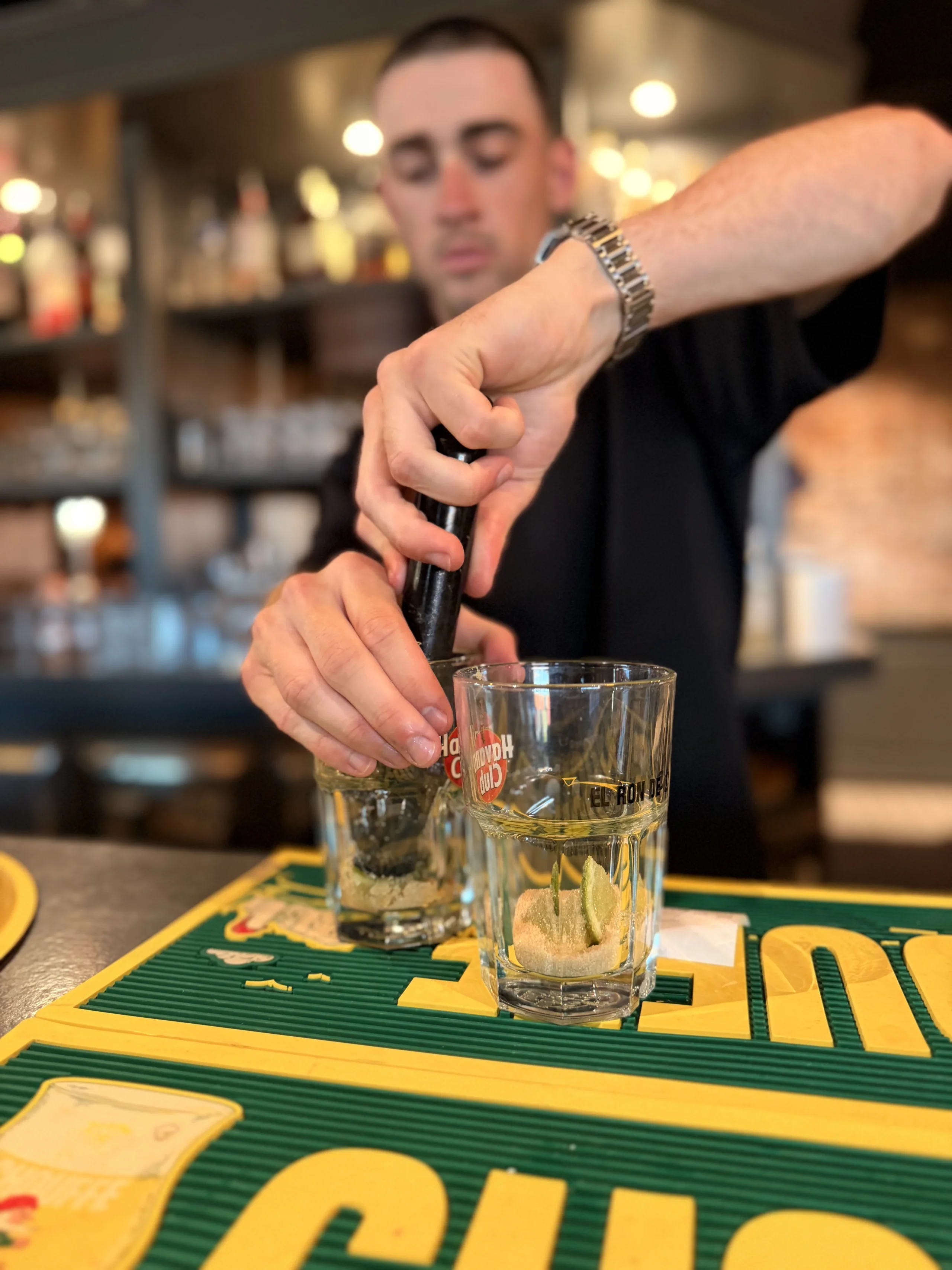 Bartender muddling cocktail ingredients behind bar counter