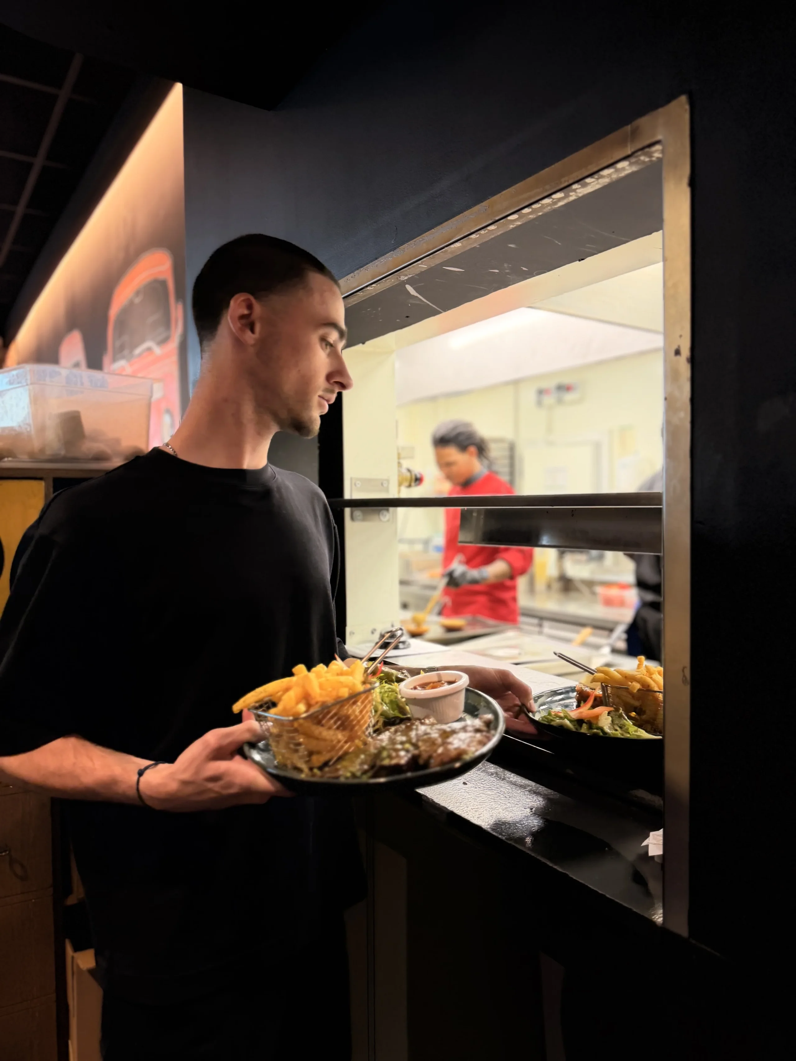 Man carrying steak and fries at restaurant pass