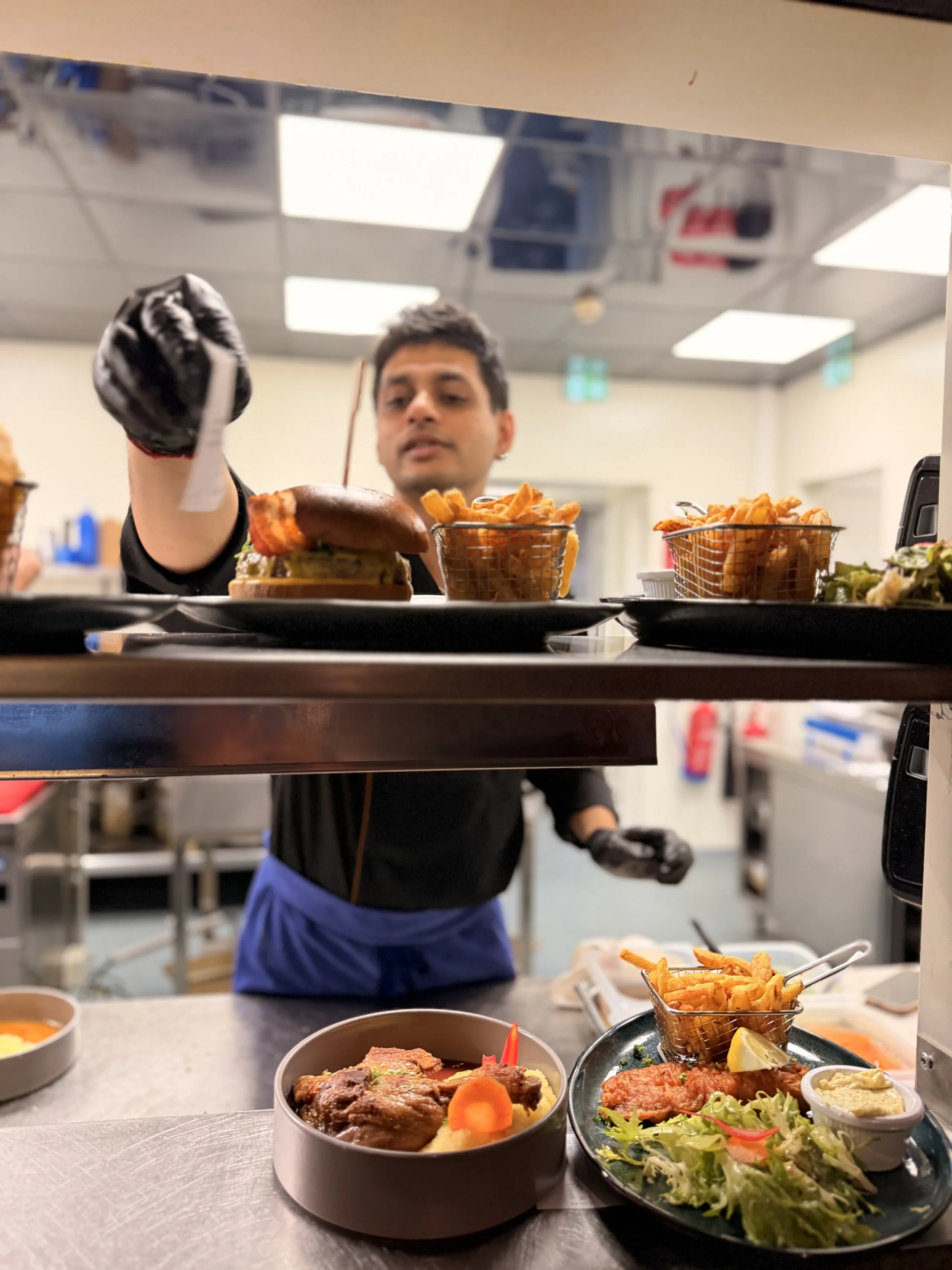 Chef plating burger and fries in kitchen