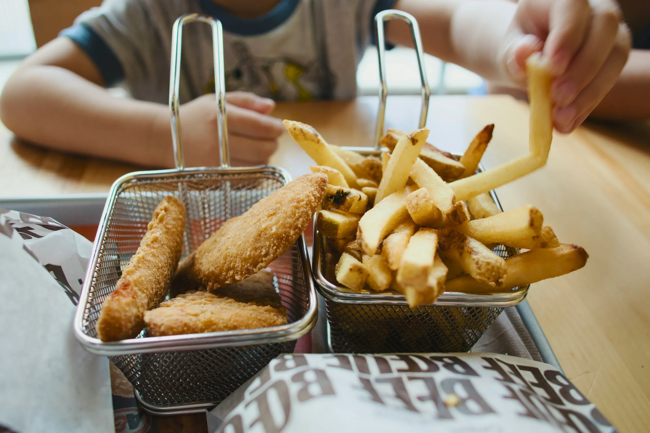 Child reaching for fries and fried snacks